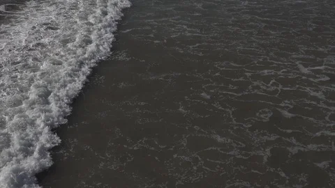 Sets of ￼small foamy waves roll in on the beach￼ Stock Footage 121305971