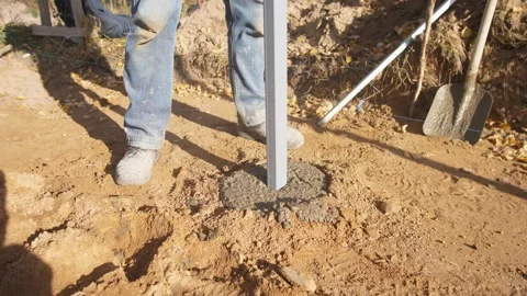 Setting and aligning metal post into wet concrete, precise installation of metal Stock Footage 319692265