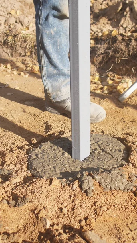 Setting and aligning metal post into wet concrete, precise installation of metal Stock Footage 319704729