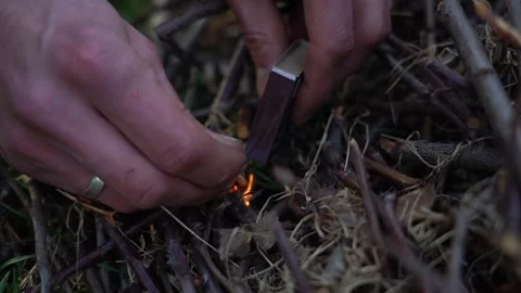Setting fire to a pile of dry branches with matches. The man strikes a match Stock Footage 306009378