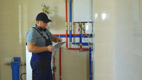 Setting up heat sensors using tablet app. Modern plumber adjusts boiler Stock Footage 319506942