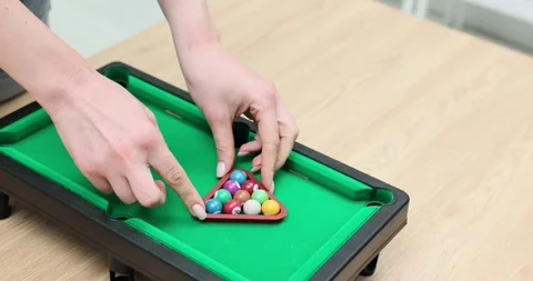 Setting up a miniature pool game with colorful balls on a green felt table Video stock 296674484
