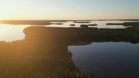 Setting northern sun flares in frame in aerial view of boreal lakes Stock Footage 345417716