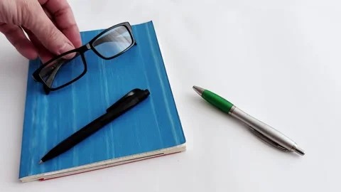 Setting Up for Study: Essential Tools - Glasses, Blue Book, Pen Ready 스톡 동영상 313043513
