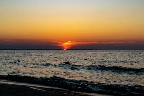The setting sun against the backdrop of a calm sea Stock Photos