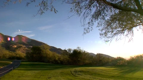 Setting sun and mountains on golf course with trees and shrubs Stock Footage 125274514