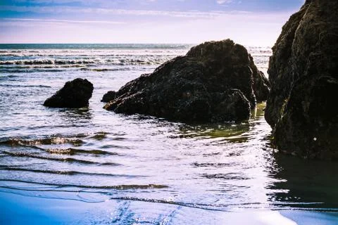 Setting sun backlight srock formations in shallow water at the beach Stock Photos