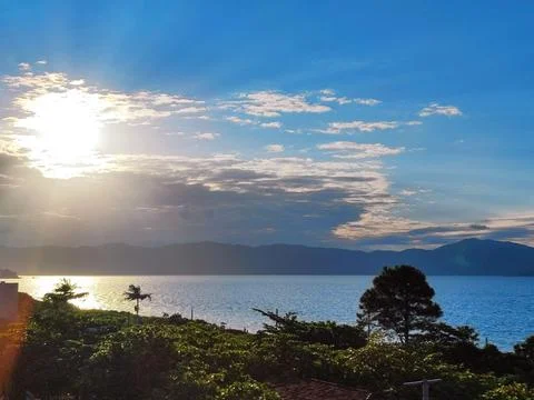Setting sun behind the clouds above the sea Stock Photos