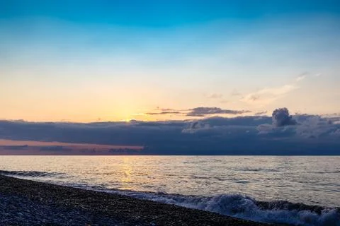 Setting sun behind clouds in dark blue sky Stock Photos
