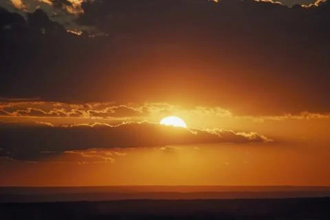 Setting Sun Behind Clouds Over Ocean Stock Photos