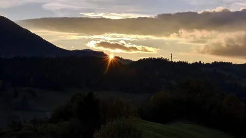 The setting sun behind the forested hills in the autumn landscape Stock Footage 261192531