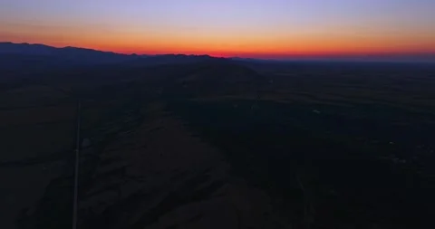 Setting Sun Behind Mountains In The Distance High Altitude Aerial Rise Vibrant Video stock 289419393