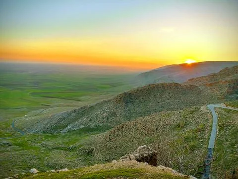 The setting sun behind the mountains rising across the Mesopotamian plain Stock Photos
