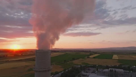 Setting sun behind of smoke out of soviet concrete factory pipe, aerial view 動画素材 303525409