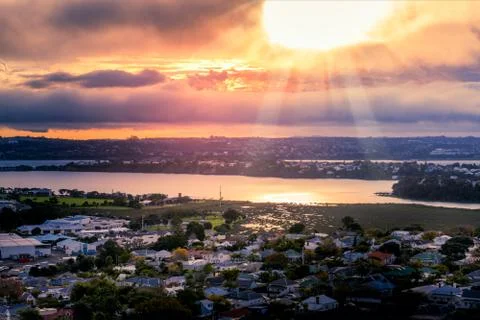 Setting sun breaking through flaming clouds over Auckland Harbour Stock Photos