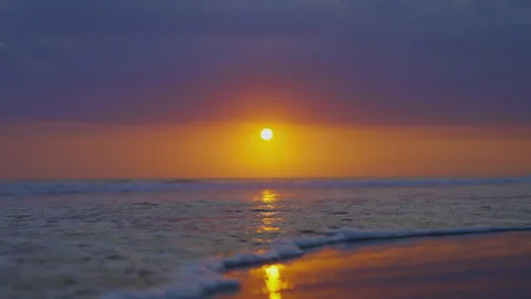 The setting sun comes out from behind the clouds against background ocean Stock Footage 275337797