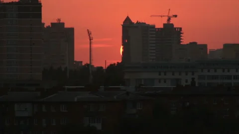 The setting sun disappears behind city buildings Stock Footage 170756196