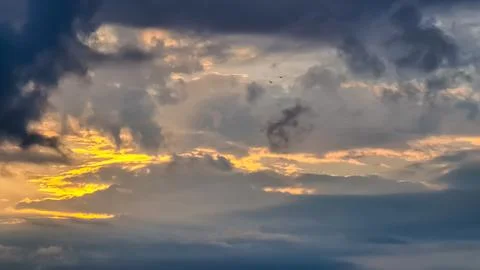 The setting sun hiding behind thick clouds. The clouds are colored yellow a.. Stock Photos