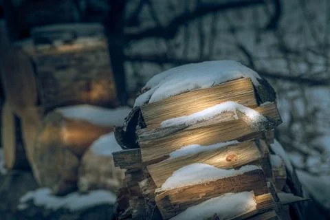 Setting sun hits the split wood pile, covered with snow Stock Photos