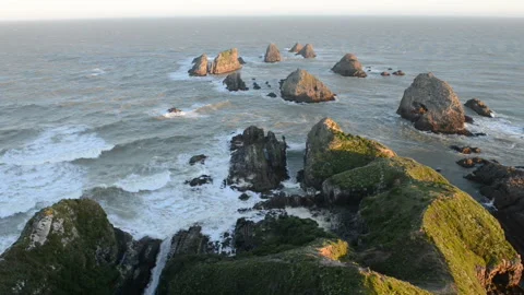 The setting sun illuminates boulders and waves of Nugget Point Stock Footage 105122514