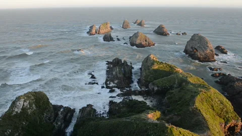 Setting sun illuminates boulders and waves of Nugget Point Stock Footage 105122946