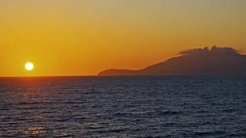 Setting sun just above ocean horizon-Distant island Stock Footage 301833099