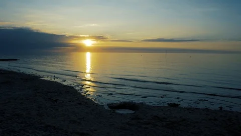 Setting sun over the horizon and reflecting its golden glow on the sea Stock Footage 94617287