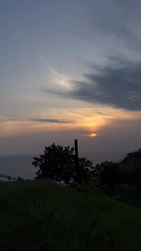 Setting Sun Over Ocean Horizon, Dark Hillside Foreground, Vertical Static Shot Video stock 324771394