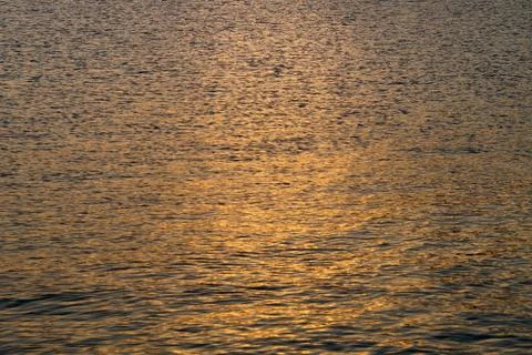 The setting sun is reflected in the dark sea water Stock Photos
