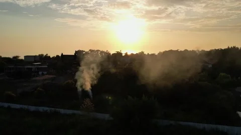 The setting sun is reflected in the lake, the yellow sunset shines black smoke Video stock 256599855