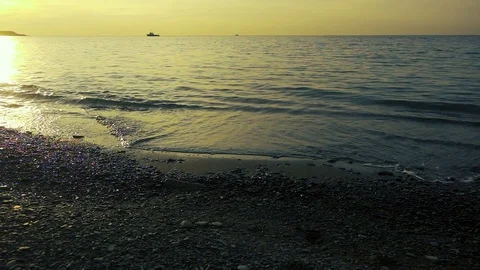 The setting sun is reflected in the sea and pebbles slow motion Stock Footage 81559584