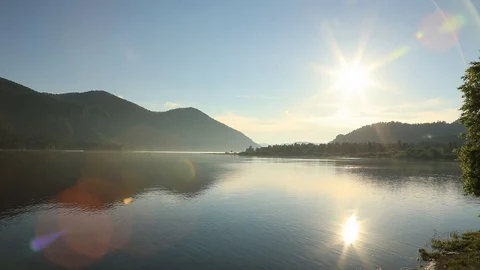 The setting sun is reflected in the water of a mountain lake.  Stock Footage 105999328