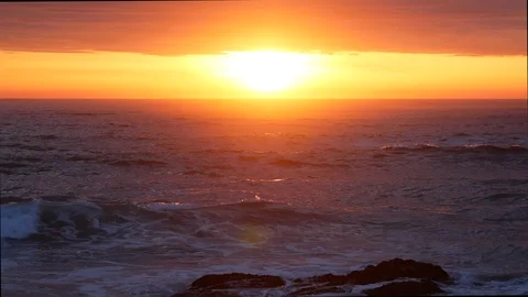 Setting sun reflected on water as ocean waves lap on the sandy beach at sunset. Stock Footage 106648320