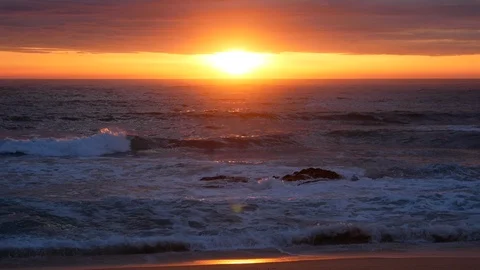 Setting sun reflecting on water on the ocean. Sandy beach at sunset. Stock Footage 106647479