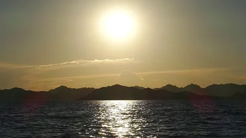 The setting sun reflects in the calm waves of the sea. Stock Footage 79686697