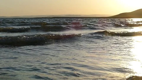 The setting sun reflects in the slowly rolling waves. Slow motion. Stock Footage 80094495