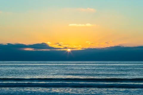 The setting sun shines through the clouds on the ocean Foto stock