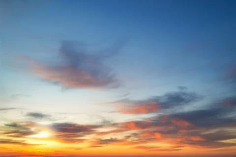 The setting sun shines through light clouds and paintes them with golden. Stock Photos