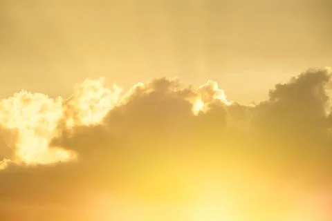 Setting sun shining through gold clouds Stock Photos