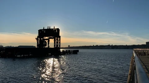 Setting sun silhouettes the ruins of old Pier 1 Gantry on the Hudson River - NYC Stock Footage 121988086