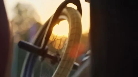 The setting sun through the BMX wheel, close-up. Cyclists in the skatepark. Stock-Footage 165740629