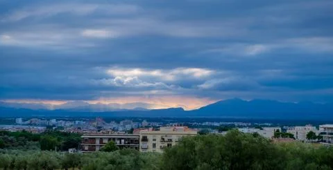 The setting sun through thick clouds illuminates Stock Photos
