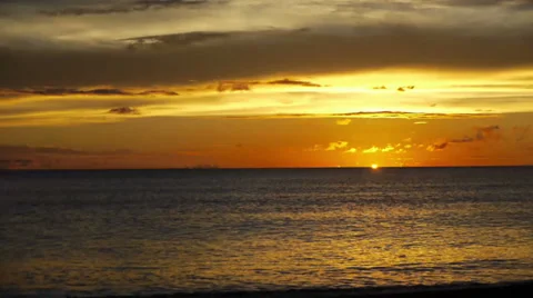 The setting sun vanishes behind the horizon, leaving behind golden skies over a  Stock Footage 32720211