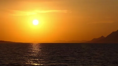 Setting sun with yellow sky on the background of the sea and the mountainous  Stock Footage 142030279