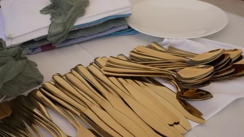 Setting a table with gold utensils and clean plates for a dining event in a brig Stock Footage 337106069