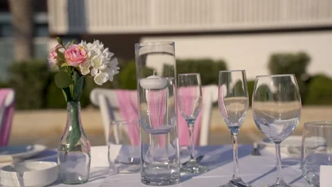 Setting the table for a meal outdoors with flowers and glassware Stock Footage 341346642