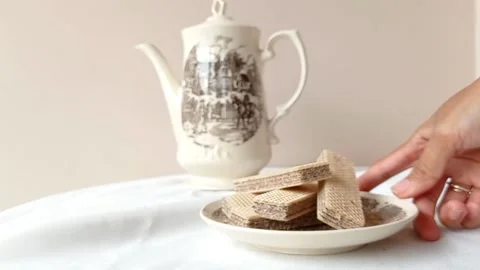 Setting up a table with a teapot and a plate of chocolate wafer Stock Footage 145561734