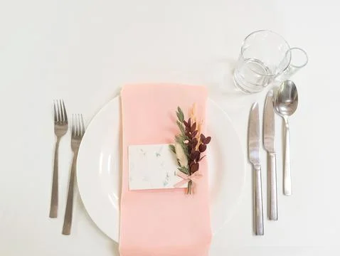 Setting the table for a wedding. Dishes, white tablecloth, flowers. Space for Stock Photos