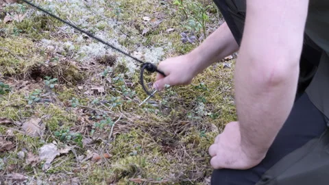 Setting Up Tent in Forest Using Rock to Secure Stake Stock Footage 334049103