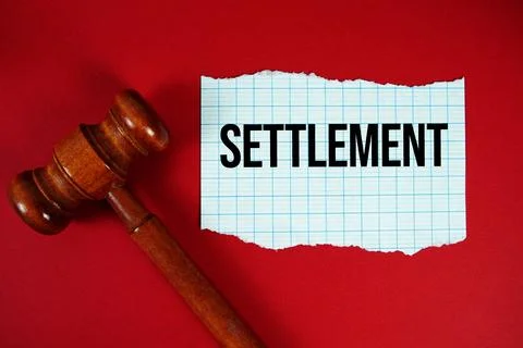 Settlement text written on rip paper with wooden judgment gavel on red back.. Stock Photos